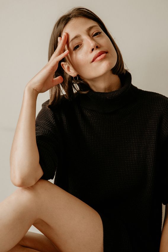 Woman in black sweater posing thoughtfully indoors.
